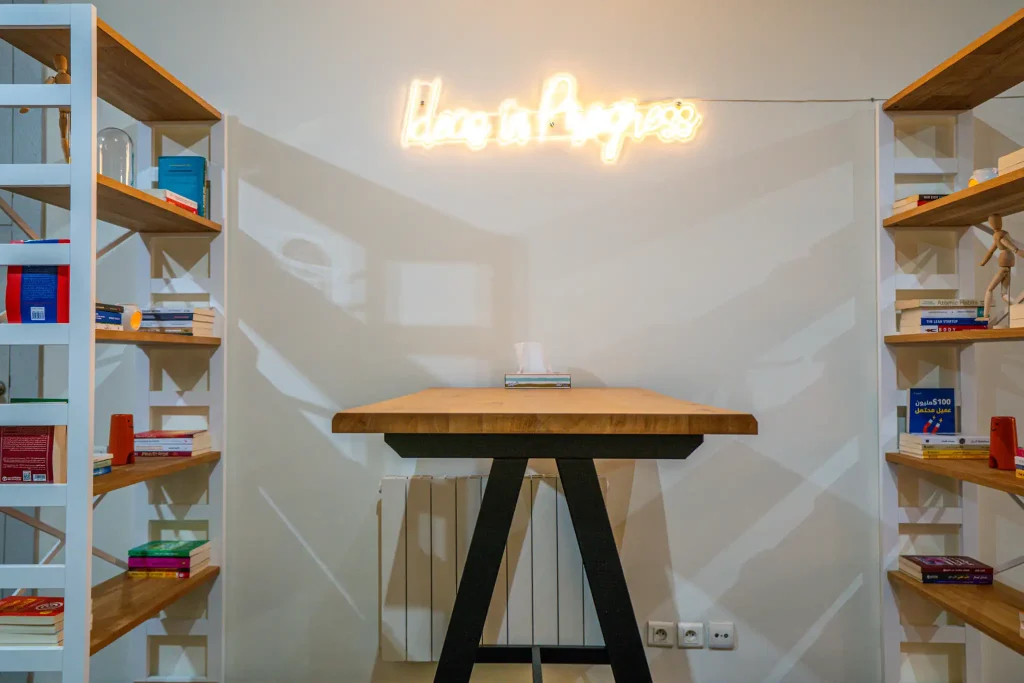 Wooden work table in front of a neon wall sign